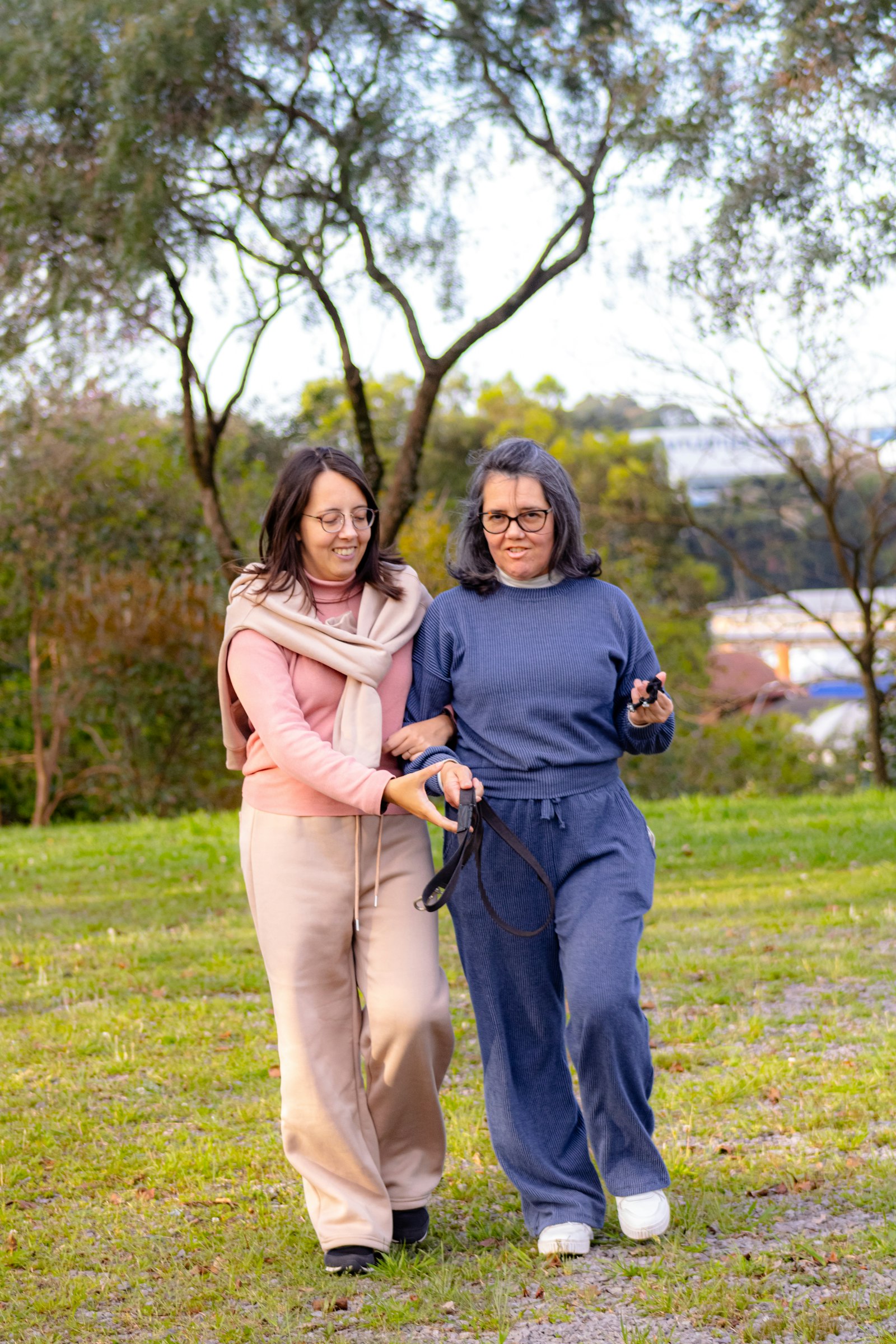 A Direct Support Professional walking arm-in-arm with a participant in a park, the kind of community-based support our program will provide